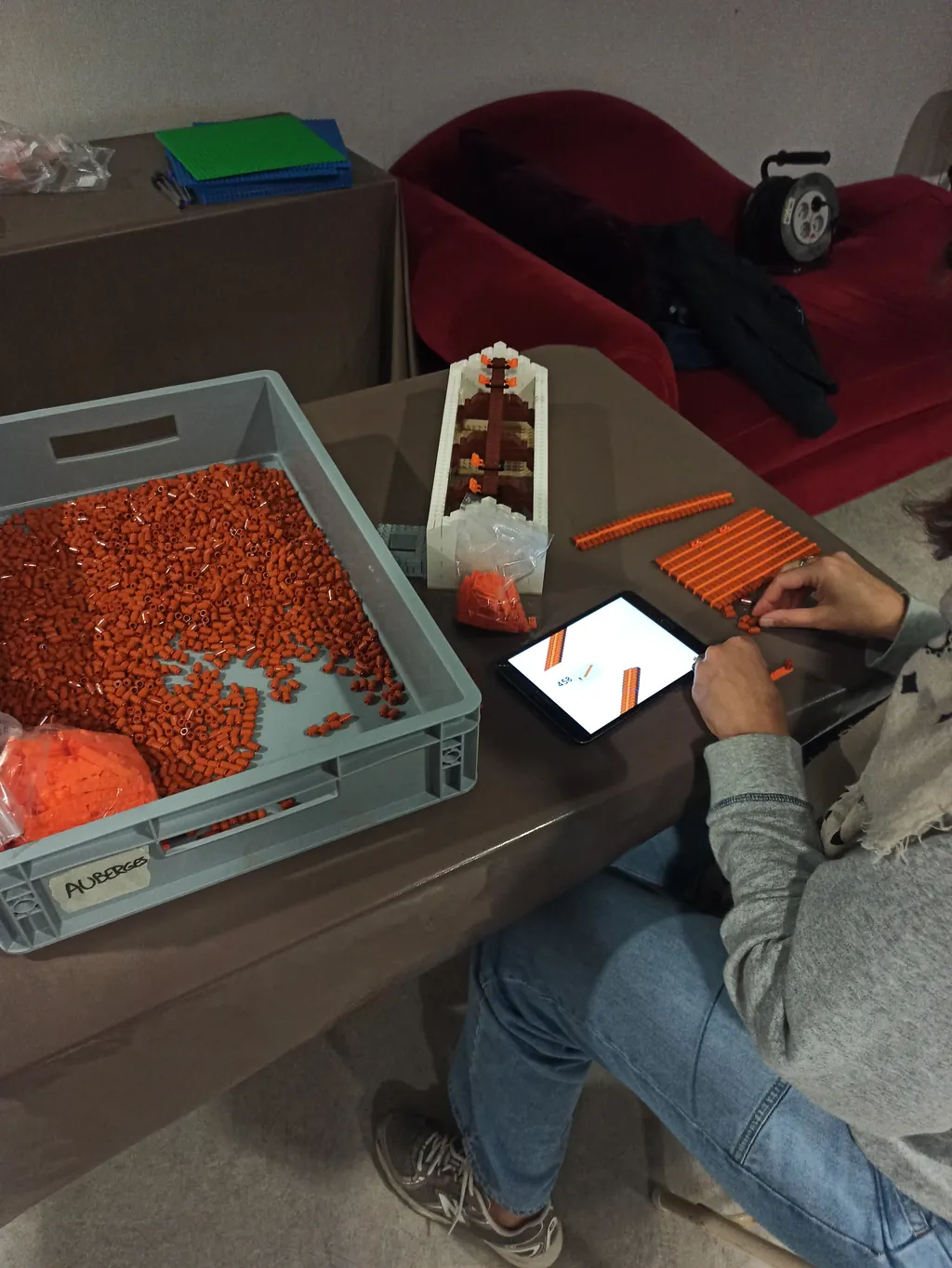 Bac de tuiles orange et plan de montage posés sur la table d'atelier