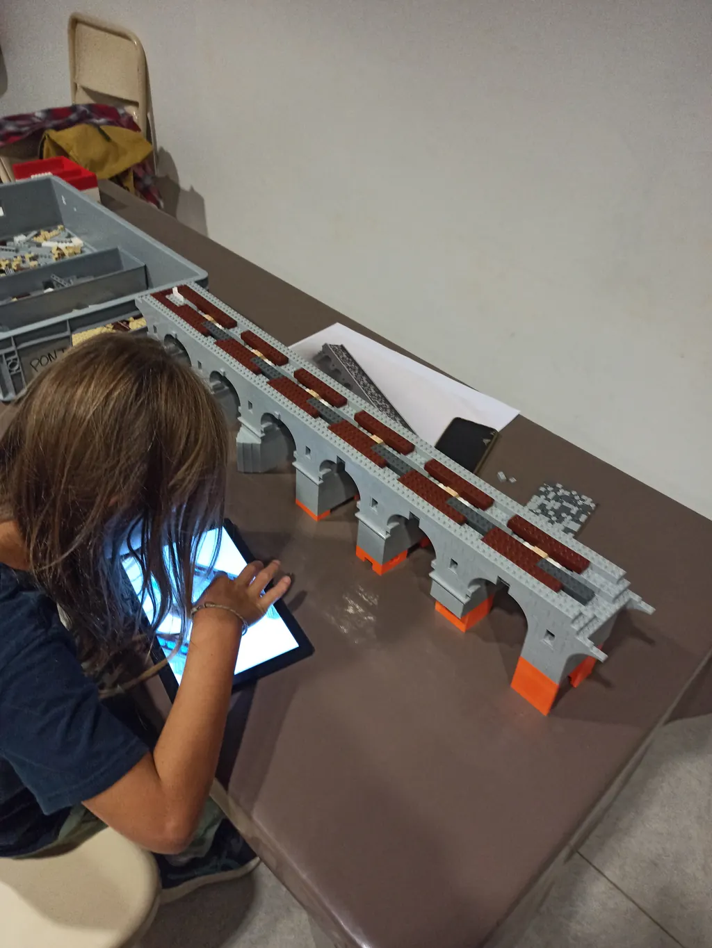 Jeune participante consultant le plan sur tablette devant le pont à arches en briques