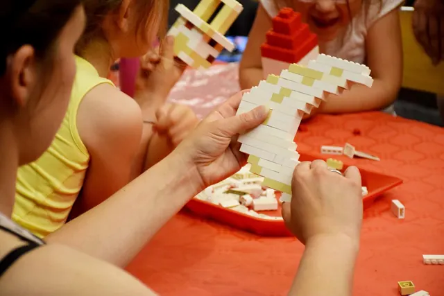 Enfants et adultes construisant librement dans un espace de briques