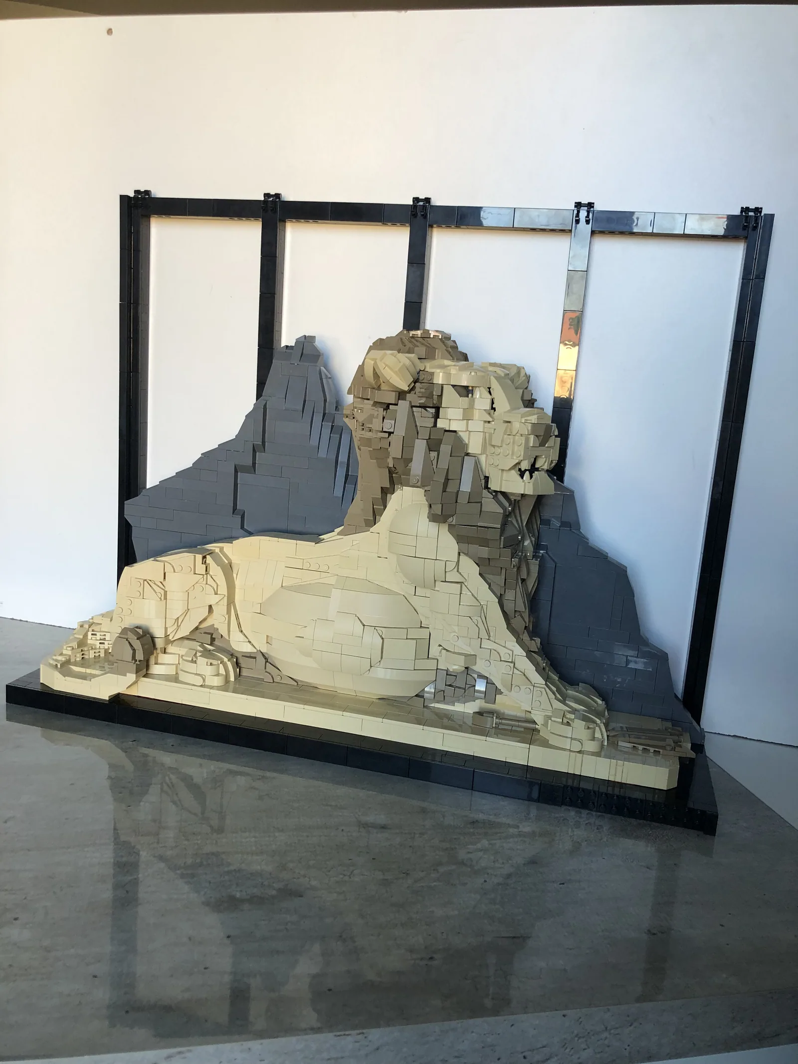 Le Lion de Belfort reproduit en briques, couché contre sa paroi rocheuse, dans son cadre noir